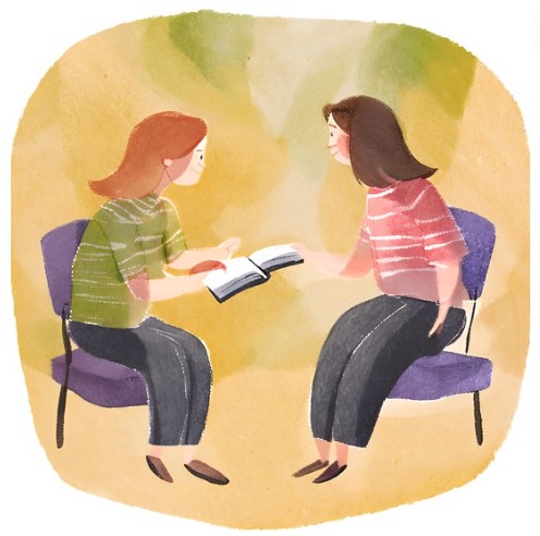 A mentor and mentee.\ looking at a book together.